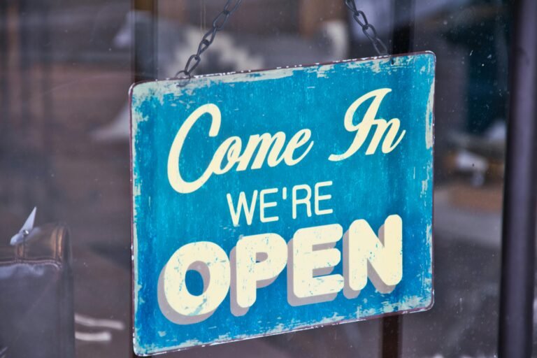 Retro blue open sign on a shop glass door inviting customers in.